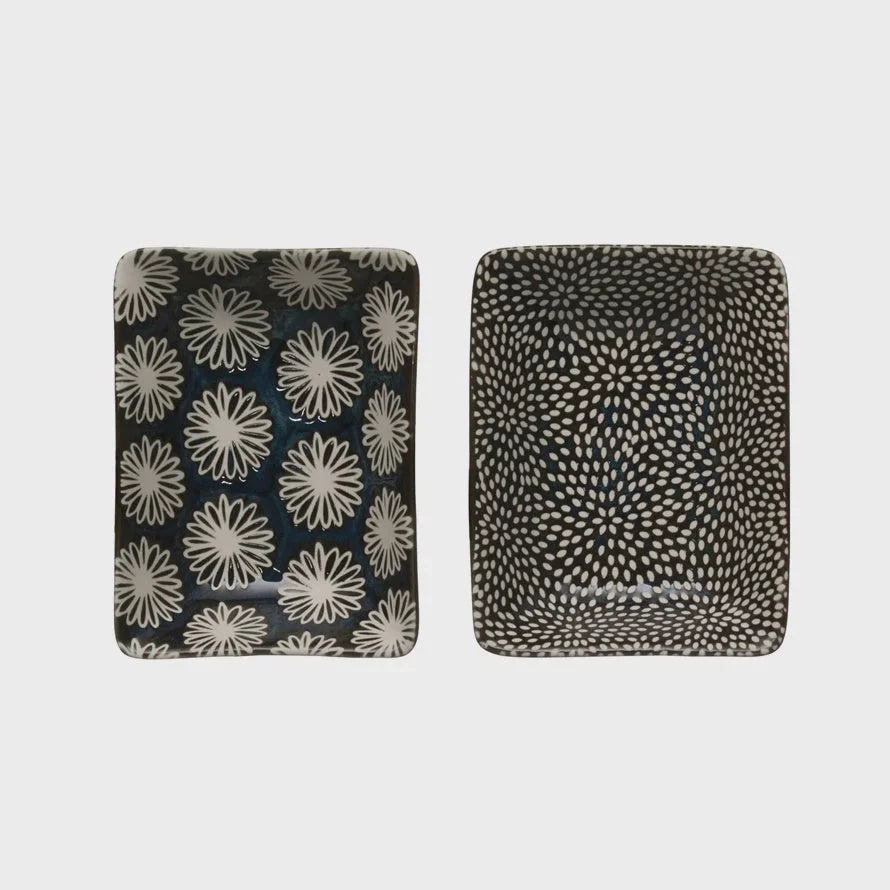 Two decorative throw blankets with floral and abstract patterns next to a mini stoneware dish