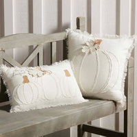 Two decorative square white pumpkin pillows on a wooden bench in autumn decor