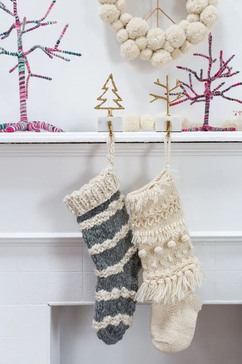 Two knitted Christmas stockings on a mantel featuring a TREE STOCKING HOLDER from Shop Daisy