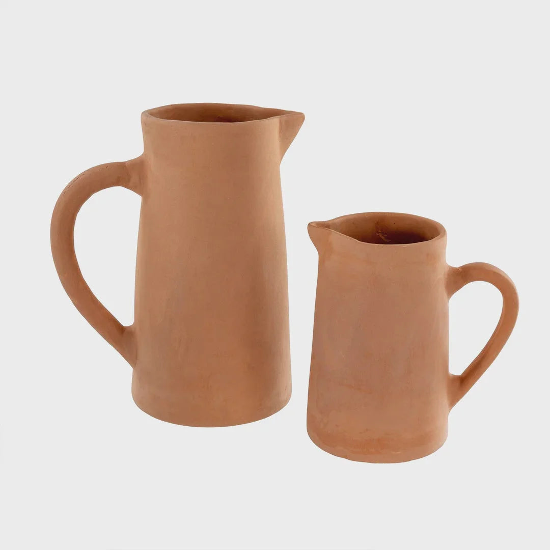 Two unglazed terracotta pitchers with handles and spouts in a boho style