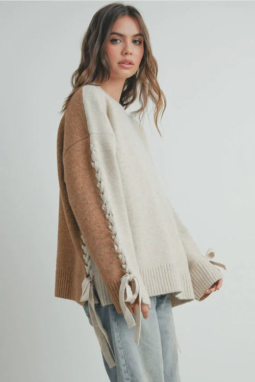 Crew neck long sleeve sweater with two-tone knit, lace-up sleeves, and bow cuffs
