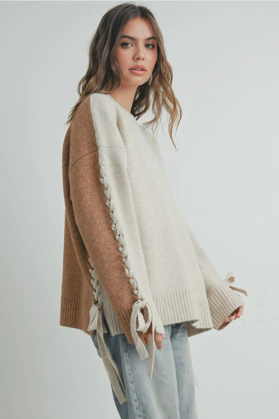 Crew neck long sleeve sweater with two-tone knit, lace-up sleeves, and bow cuffs