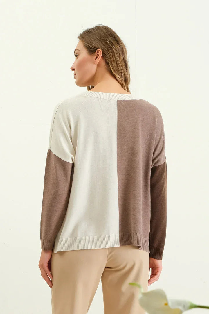 Woman wearing a relaxed colorblock sweater with cream and taupe panels from behind