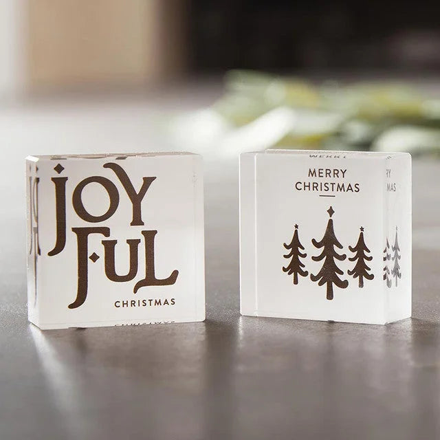 Two white decorative Christmas themed lucite blocks with festive messages and designs