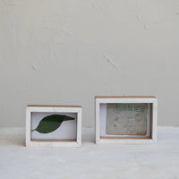 Two white wooden shadow box photo frames with a green leaf and a handwritten note