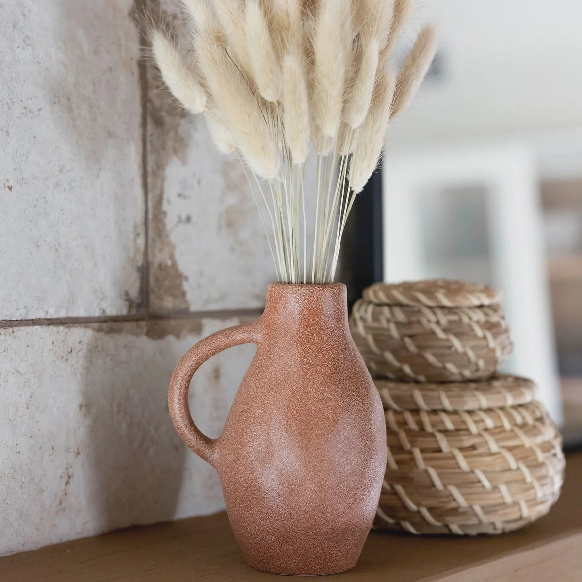 Bunny tail arrangement in a blush ceramic vase displayed on a shelf