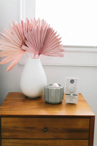 Vase with pink paper flowers atop dresser featuring Sweet Grace scented wax bar