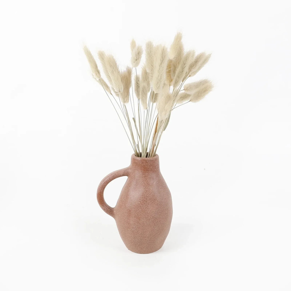 Bunny tail arrangement in a blush ceramic vase with elegant white feathers