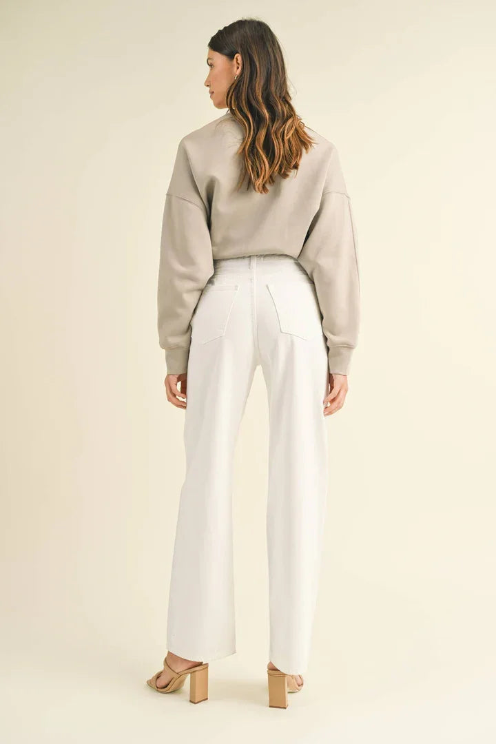 Back view of a person in a beige cropped sweater and white wide-leg pants with skater jeans