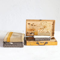 Weathered wooden suitcase with folded cotton knit tea towels beside it