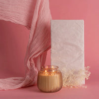 White candle and pink scarf on pink background featuring Sweet Grace Candle Passion Fruit & Patchouli