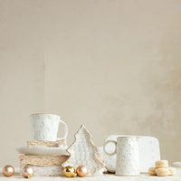 White ceramic debossed stoneware Christmas mug shaped like a Christmas tree with gold accents