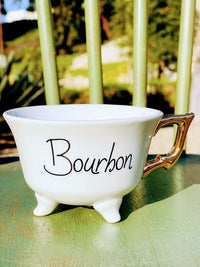 White stoneware footed teacup with Bourbon design and small gold electroplating feet