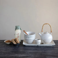 White ceramic teapot with bamboo handle displayed alongside a stoneware mini bowl