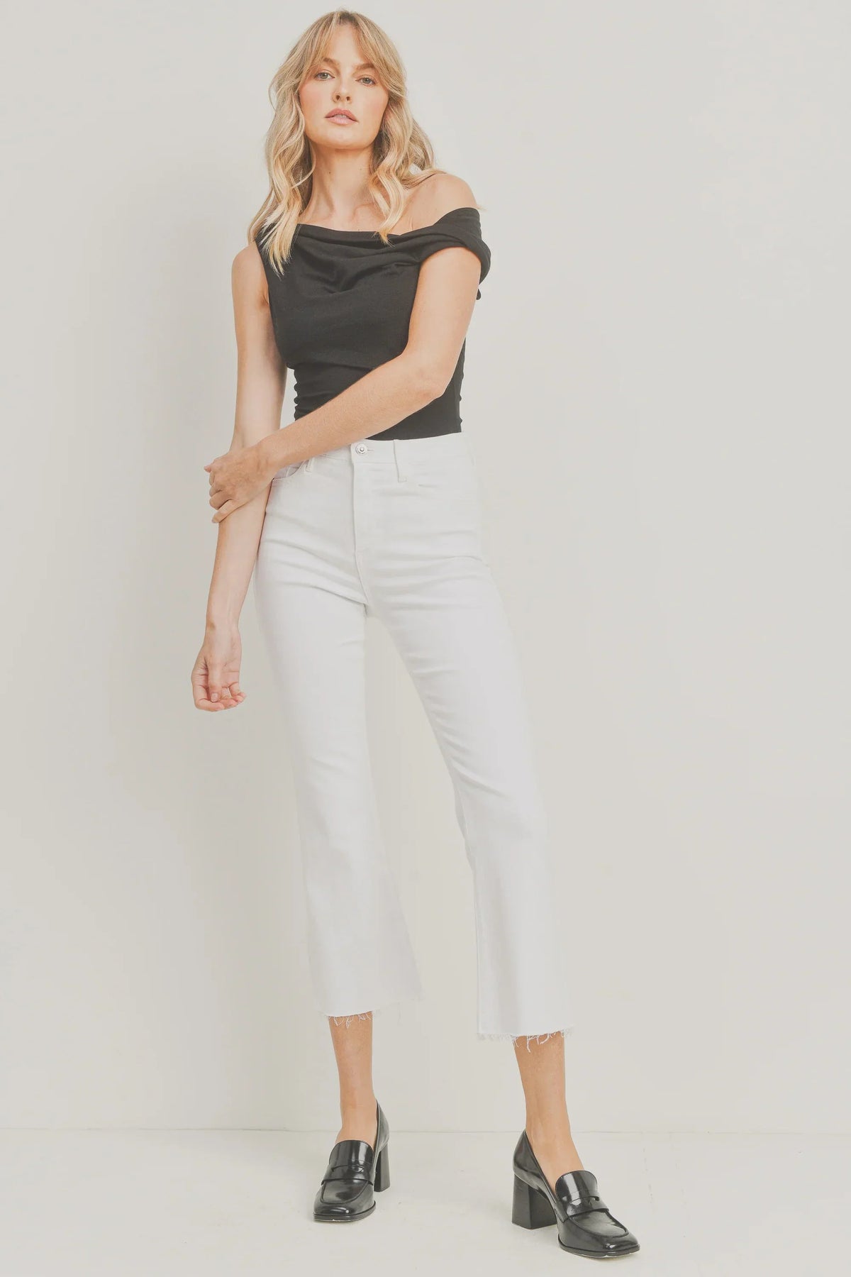 White cropped flare denim styled with a black off-shoulder top and loafers