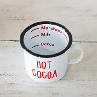 White enamel mug with hot cocoa design, black rim, and fill level markings inside