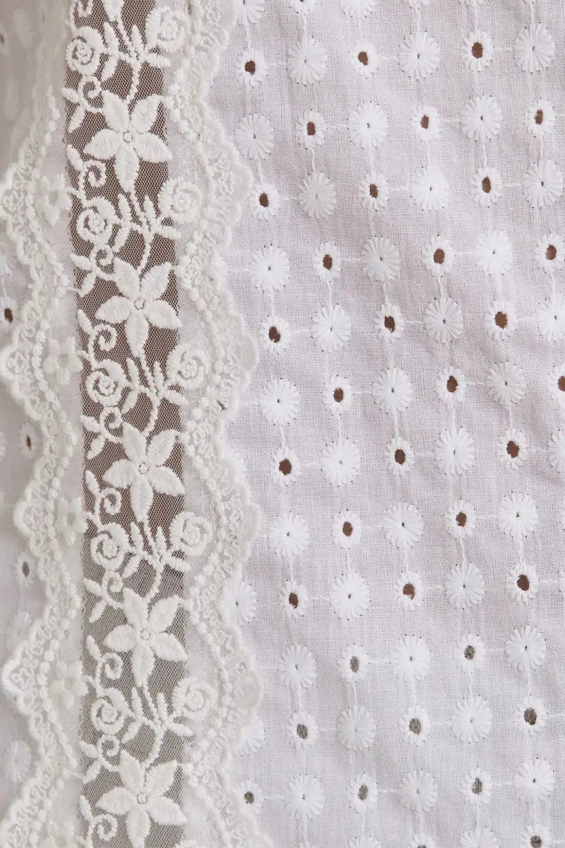 White eyelet fabric with floral lace trim showcases women’s boho chic clothing, shop Daisy