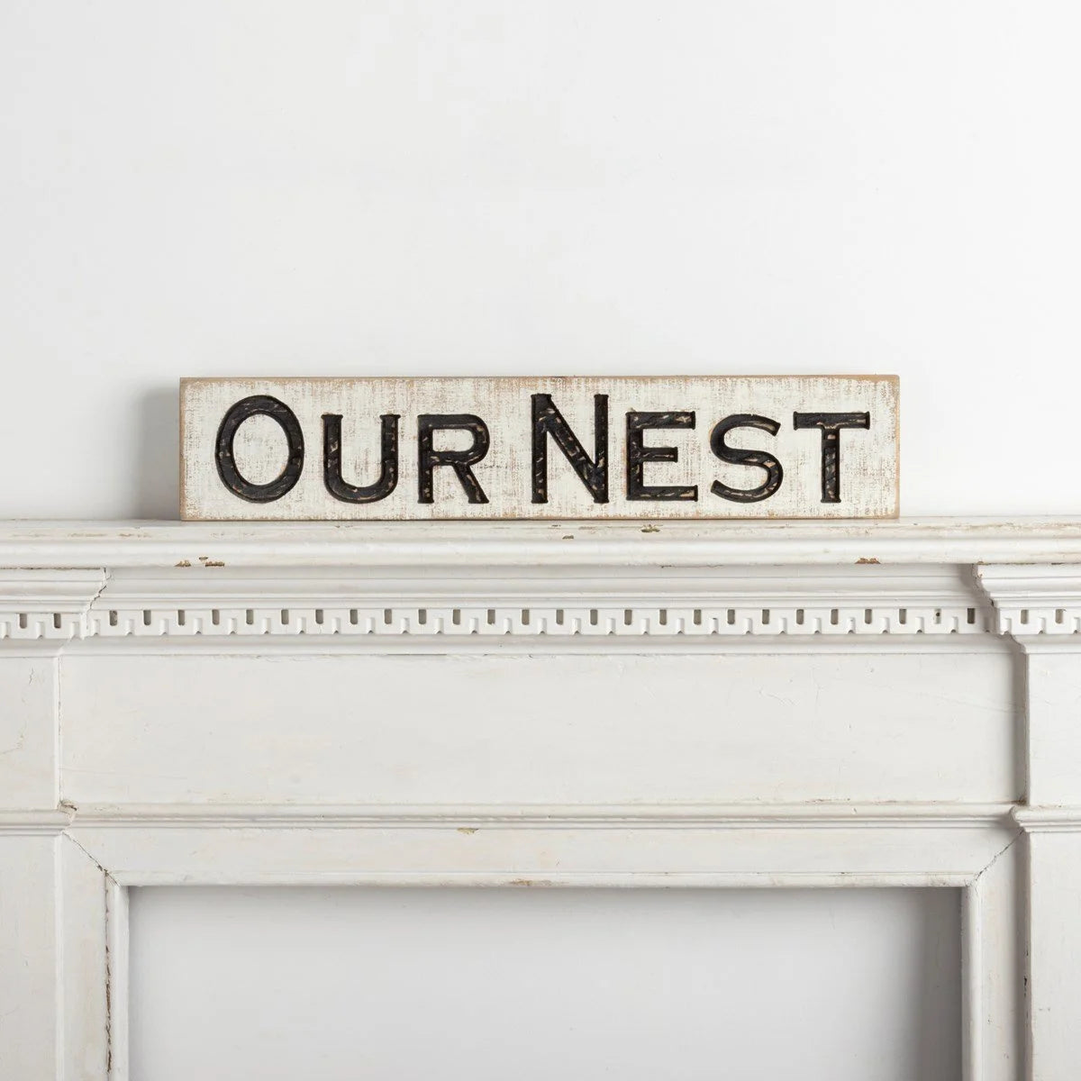 White fireplace featuring OUR NEST CARVED SIGN with the word Orient