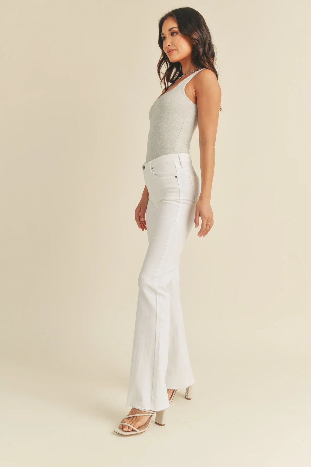 White mid rise flare denim jeans styled with a light-colored sleeveless top