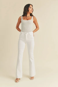 White mid rise flare denim jeans styled with a white tank top for a chic look