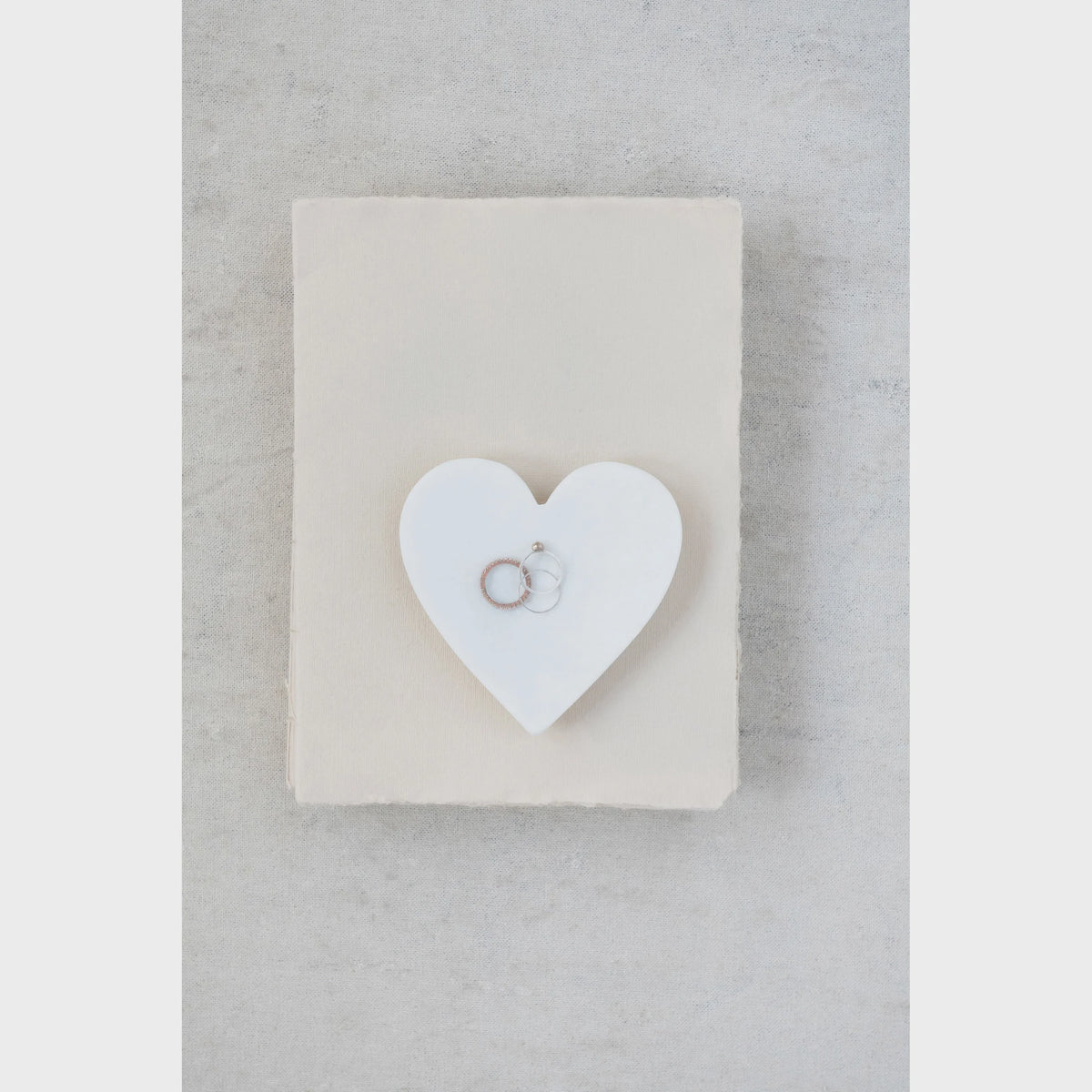 Elegant marble heart dish with small ring symbol on beige background from Shop Daisy