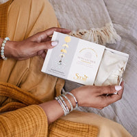 Elegant white card with gold accents held by hands in beaded bracelets, showcasing Suncatchers Gemstone