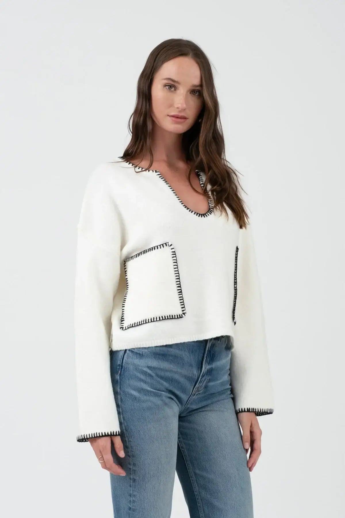 White knit sweater with black trim and pockets, ideal for women’s boho chic clothing at Shop Daisy