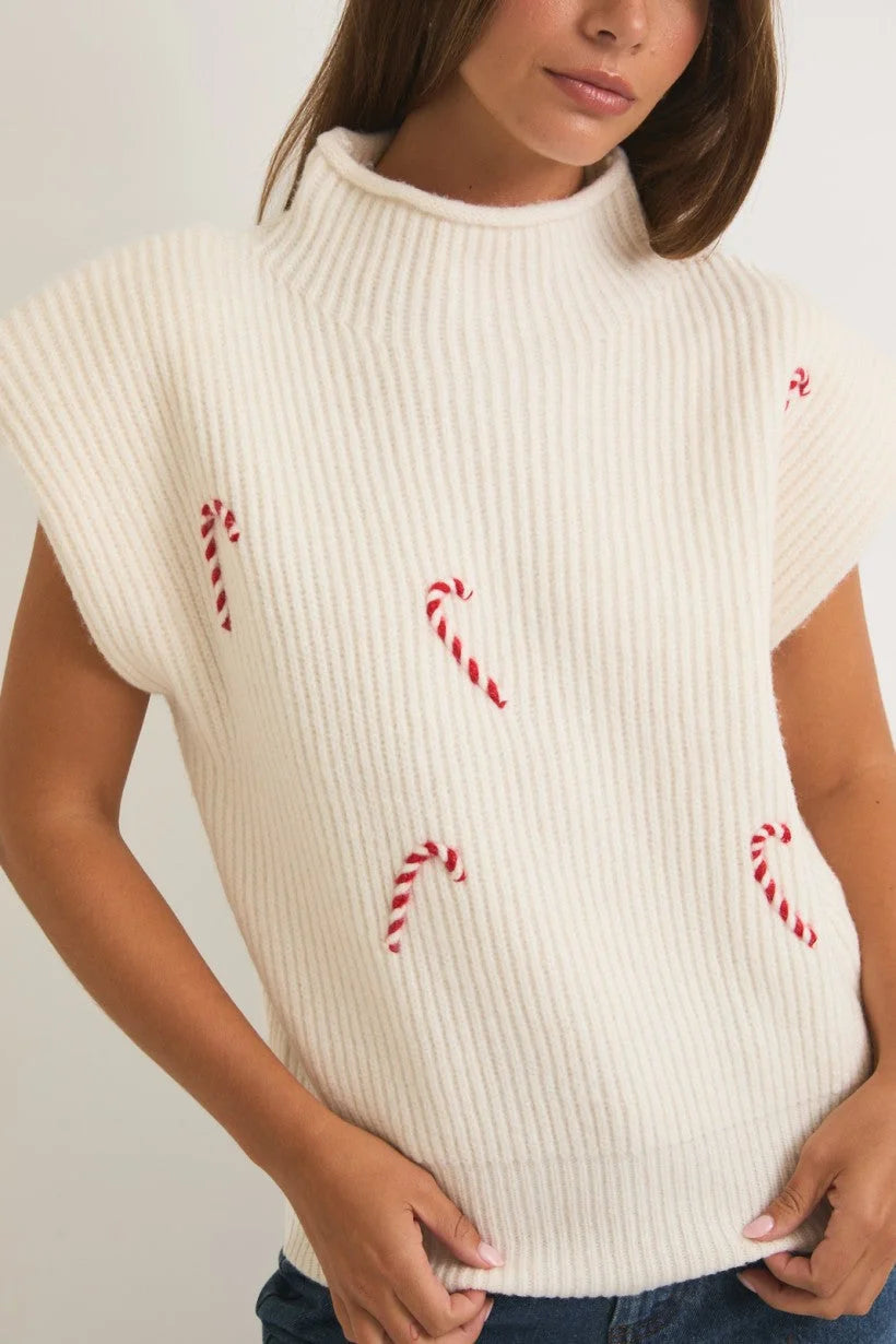 White mock neck power shoulder sweater vest featuring festive red candy cane designs