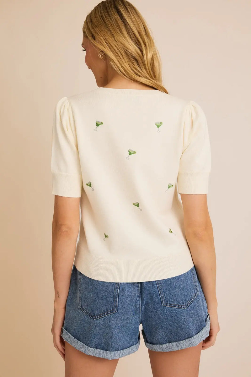 White puff sleeve embroidered knit top featuring green triangles on the back