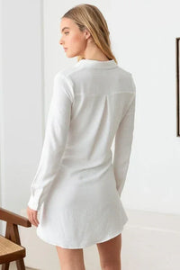 White long-sleeved flowy mini dress worn by a woman from behind showcasing boho style