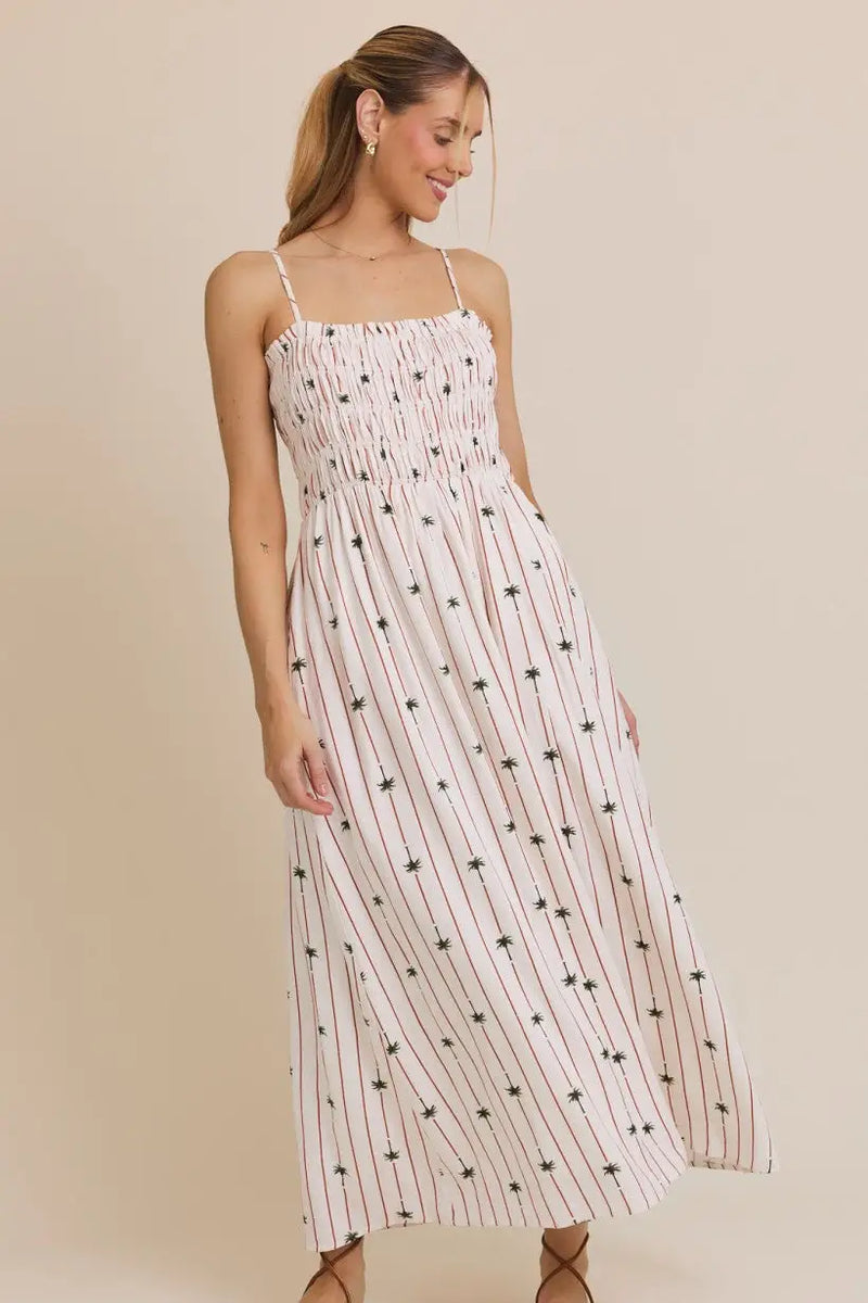 White smocked maxi dress featuring a vibrant palm tree print, perfect for summer outings