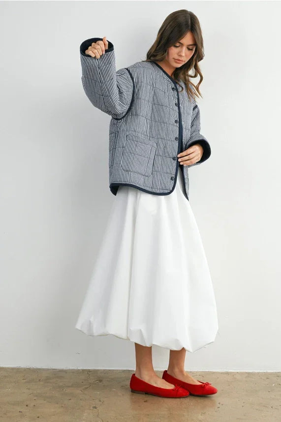 Buttoned quilted puffer jacket with white pleated skirt and red ballet flats
