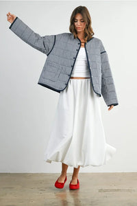 Buttoned quilted puffer jacket with white pleated skirt and red heels