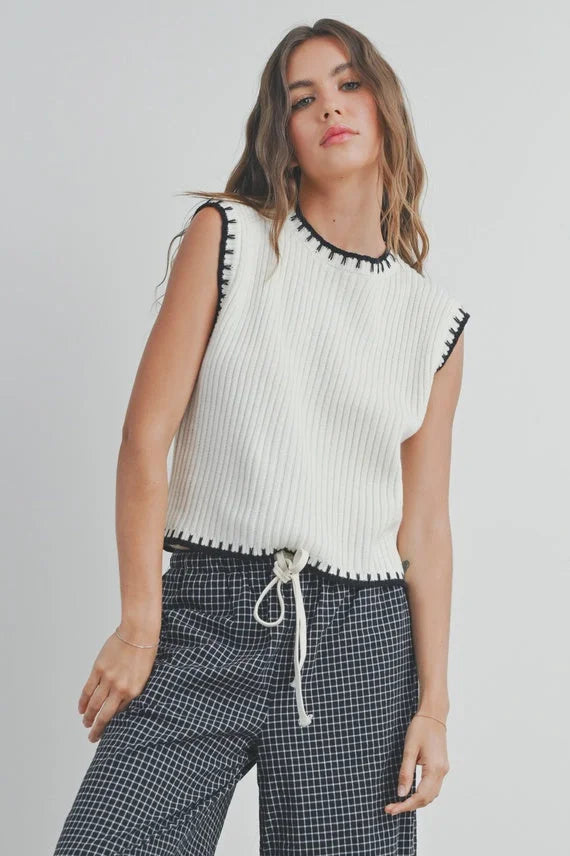 White ribbed knit cap sleeve sweater vest with black trim and drawstring hem
