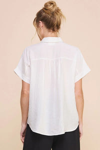 White textured short sleeve button shirt worn by a person with blonde hair in a bun