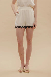 White shorts with contrast wavy hem and black scalloped trim for stylish summer wear