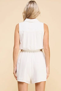 Back view of a white sleeveless collared button front romper, featuring shorts