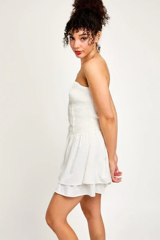 White strapless mini dress featuring a layered skirt and smocked bodice tube design