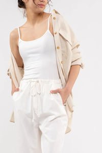 White spaghetti strap tank top styled with drawstring pants and beige overshirt for women’s boho chic clothing