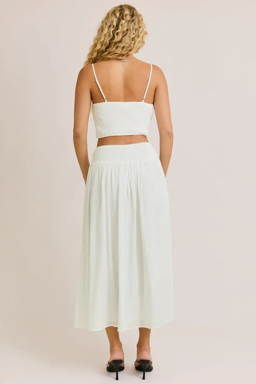 White two-piece skirt set featuring a smocked spaghetti strap crop top from Daisy Lane Offers