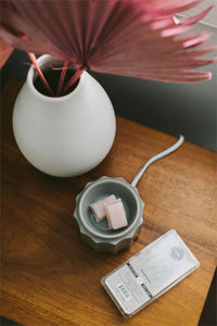 White vase with pink flower and candle near Sweet Grace Scented Wax Bar