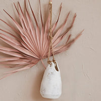 White vase with pink leaves in a Hanging Coarse Stoneware Planter with jute rope hanger