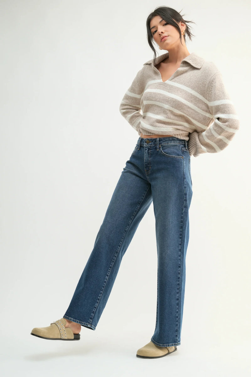 Wide-leg blue jeans paired with a cropped beige sweater and tan sneakers for stylish look