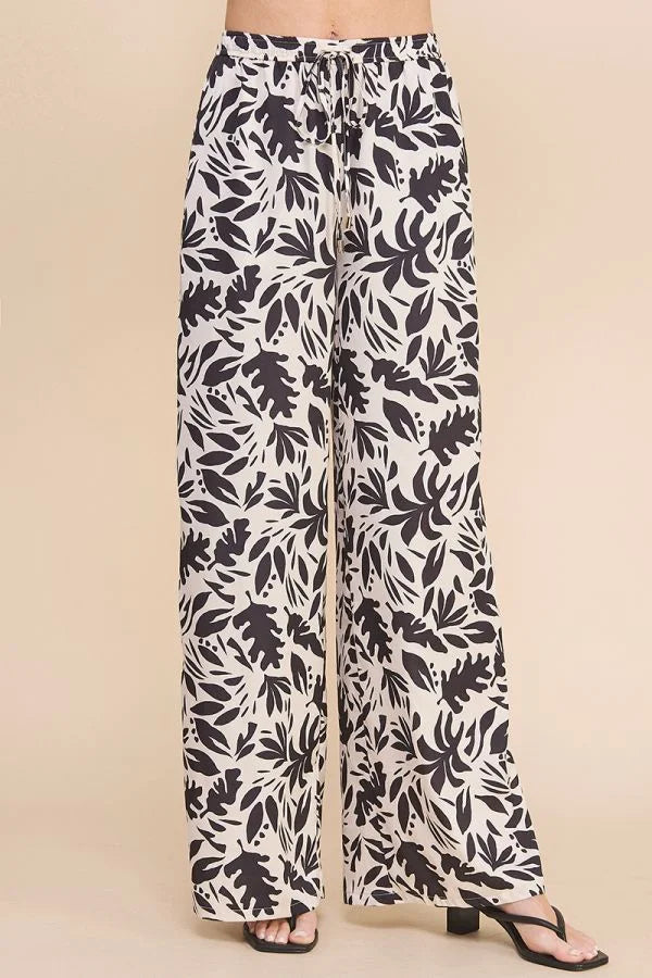 High waisted wide leg pants in black and white leaf print pattern, printed satin style