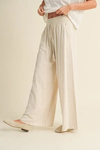 Wide-leg white trousers with a high waistband, featuring cotton linen smocked design