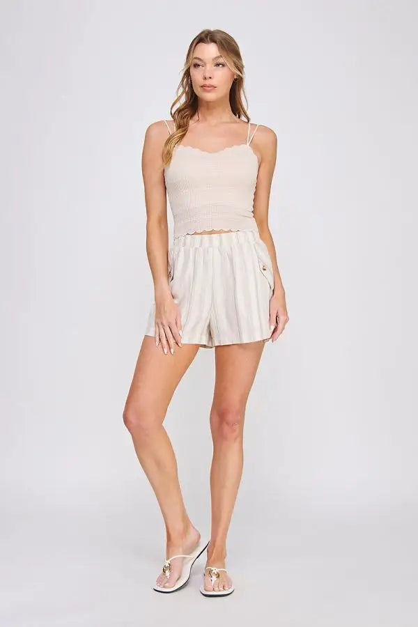 Woman in beige camisole and striped shorts wearing Daisy Lane’s scallop edge bralette with whimsical trim for a flirty silhouette
