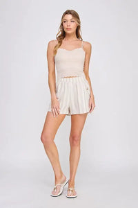Woman in beige camisole and striped shorts wearing Daisy Lane’s scallop edge bralette with whimsical trim for a flirty silhouette