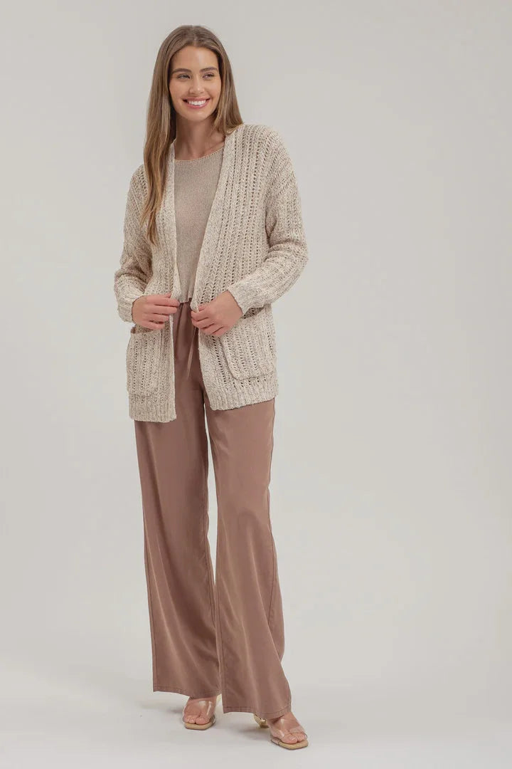 Woman in a beige crochet knit cardigan and wide-leg pants for stylish layering