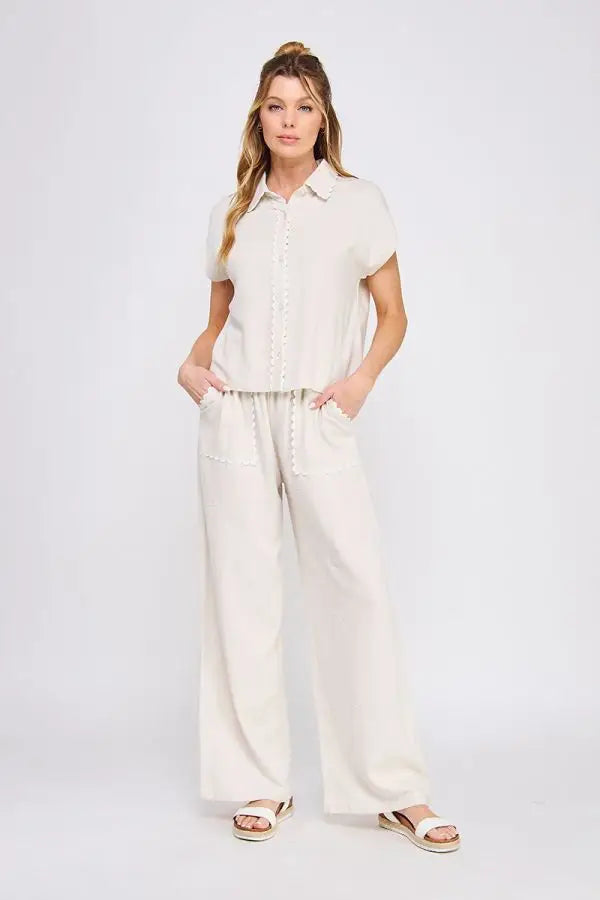 Woman wearing beige bow embroidered linen pants with scallop trim showcasing elegant linen pants