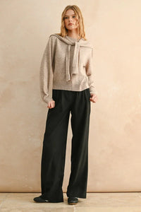 Woman modeling beige round neck sweater with matching scarf and black wide-leg trousers
